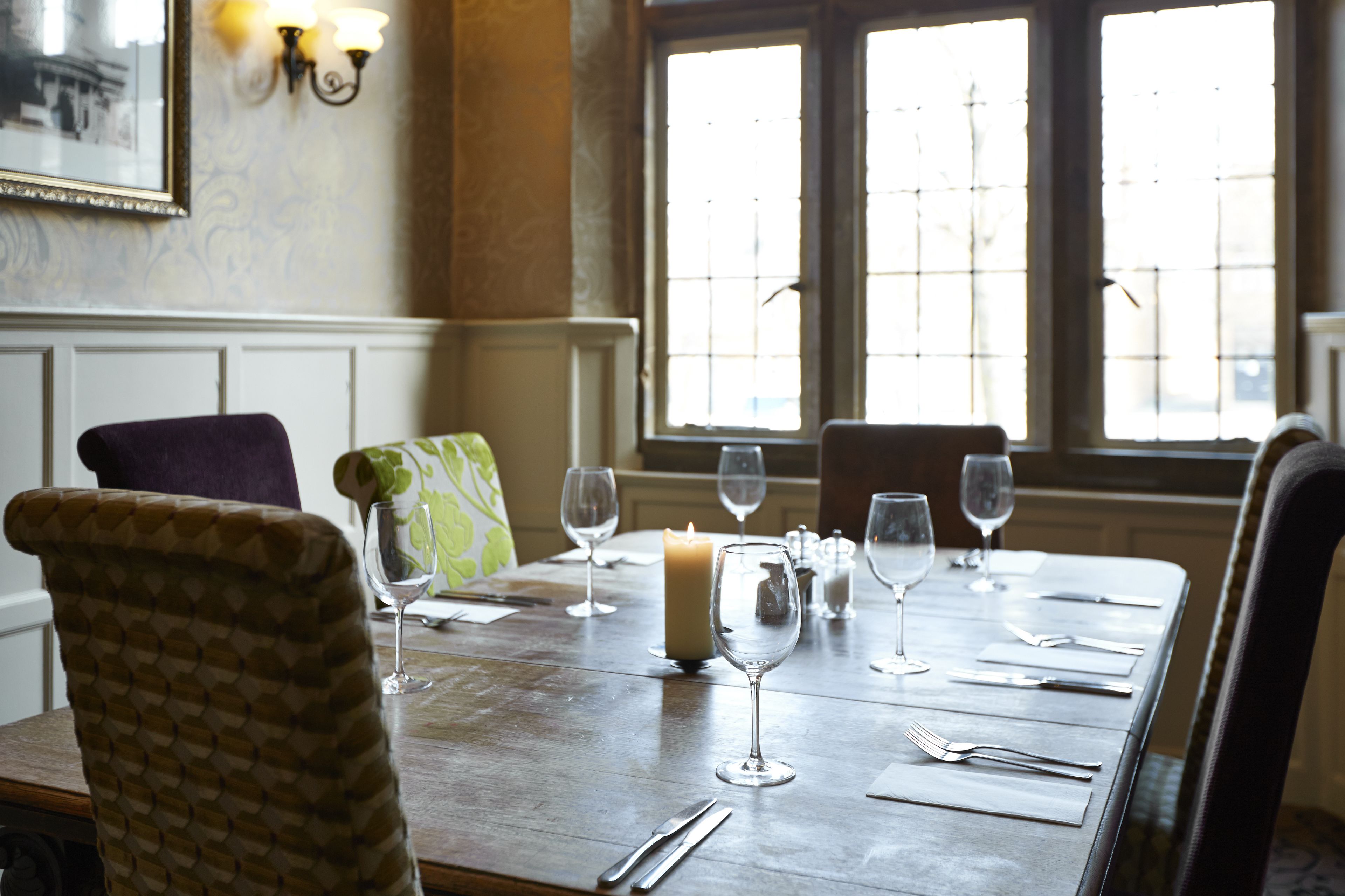 A dining table set with wine glasses, a candle, and cutlery.