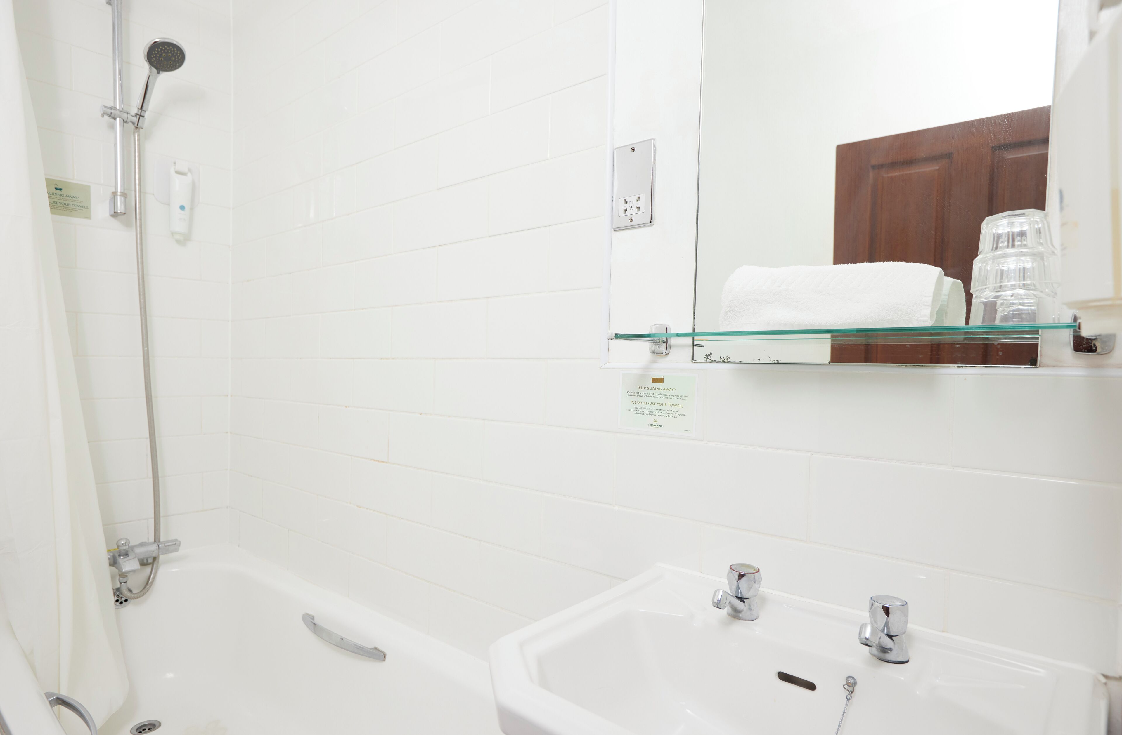 A bathroom with a glass shelf, a bathtub, a sink, and a shower.