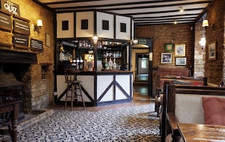 Un pub con zona de bar, muebles de madera y suelo estampado.