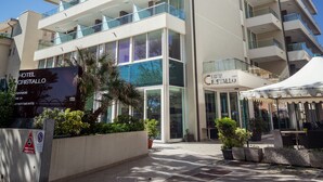 Un hôtel à plusieurs étages doté de balcons, une enseigne indiquant la présence de 133 appartements avec cuisine, et un auvent blanc à l’extérieur.