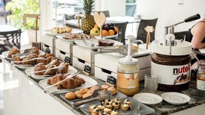 Un buffet proposant une variété de pâtisseries, un distributeur de Nutella et un saladier rempli de fruits.