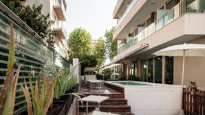 Un espace piscine extérieur moderne, doté d’une terrasse en bois, de chaises longues et d’un jacuzzi.