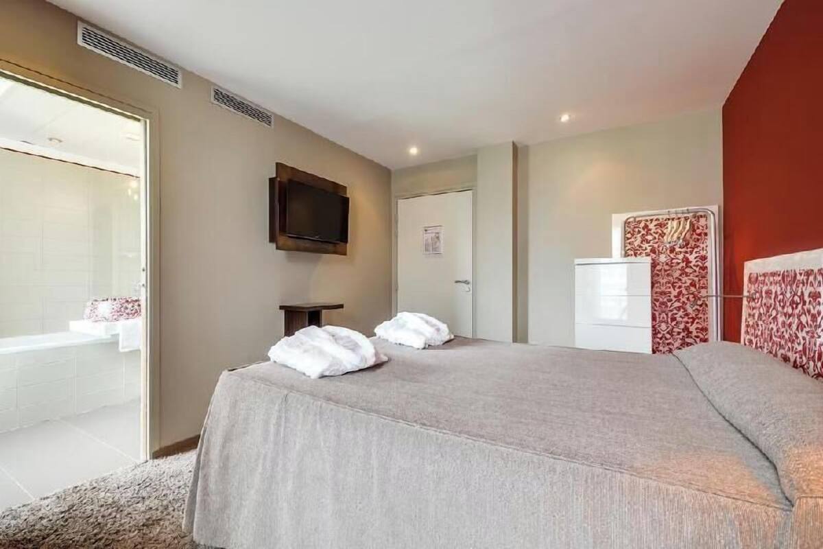 Une chambre d’hôtel comprenant un lit, une télévision, une armoire et une salle de bain avec douche et lavabo.
