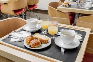 A breakfast tray with croissants, orange juice, and coffee on a table in a restaurant. - Pavillon Nation (Paris)