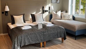 A modern bedroom with a large bed, a smaller sofa, and a window with a view of greenery. - Moss Hotel & Apartments (Moss)