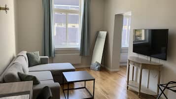 Una sala de estar moderna con un sofá, una mesa de centro, un televisor y un espejo grande.