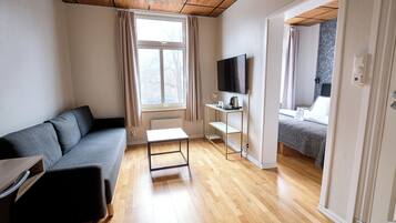 A modern room with a sofa, a small table, a TV, and a bed with a patterned wall.