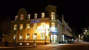 A hotel with a classic European architectural style, featuring a prominent illuminated sign and a well-lit facade.