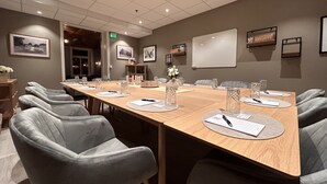 A conference room with a long table, grey upholstered chairs, and a whiteboard on the wall. - Moss Hotel & Apartments (Moss)