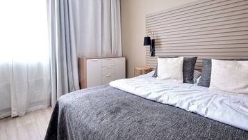 Un dormitorio con cama, cortinas, mesita de noche y lámpara de pared.