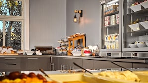 A buffet setup with various food items and a refrigerator stocked with beverages. - Moss Hotel & Apartments (Moss)