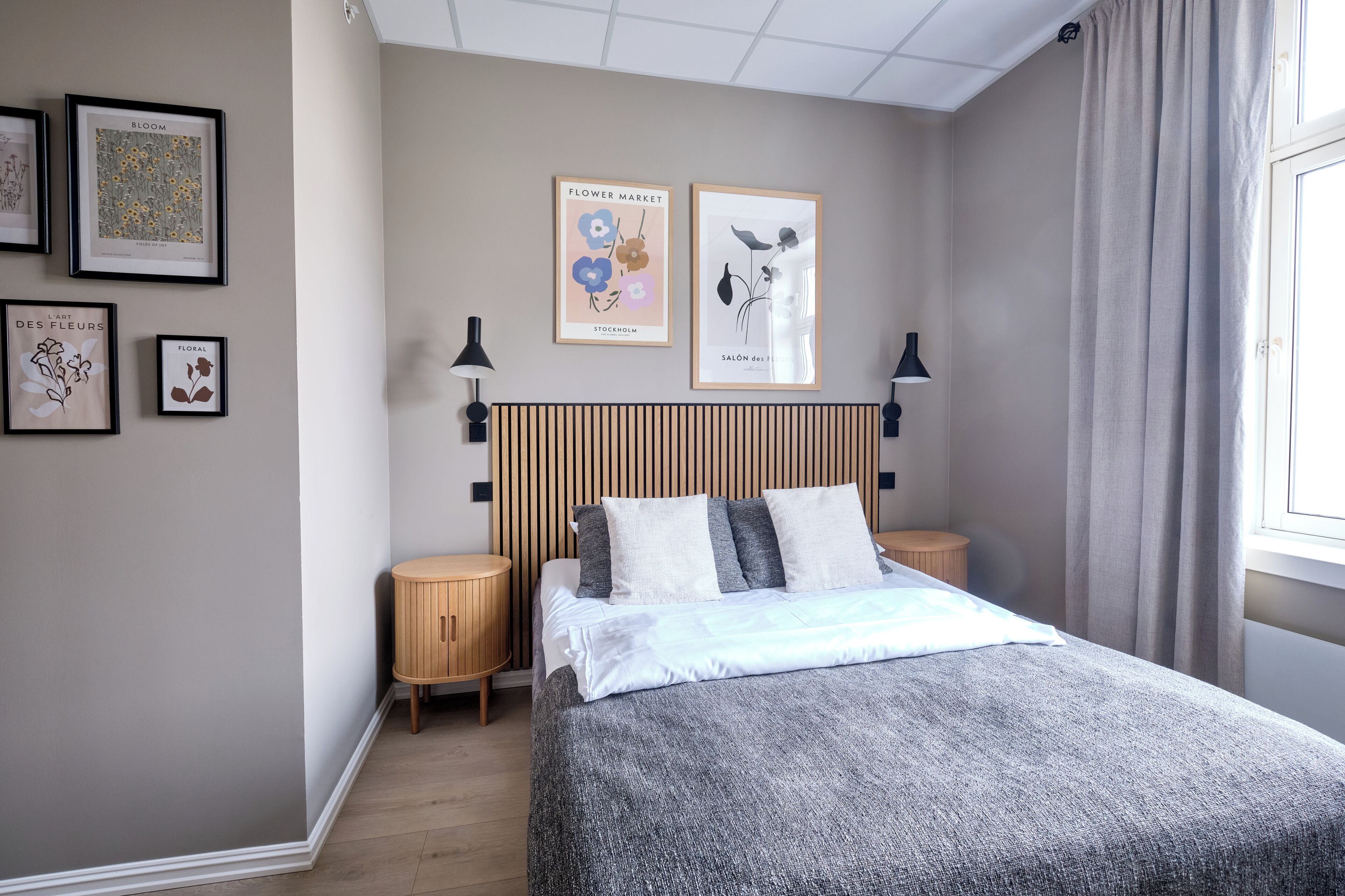 A bedroom with a bed, two bedside tables, a headboard, and framed artwork on the wall.