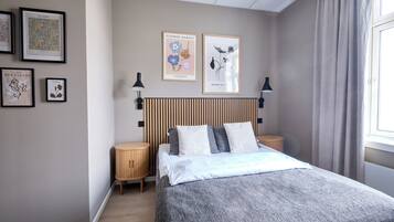 A bedroom with a bed, two bedside tables, a headboard, and framed artwork on the wall.