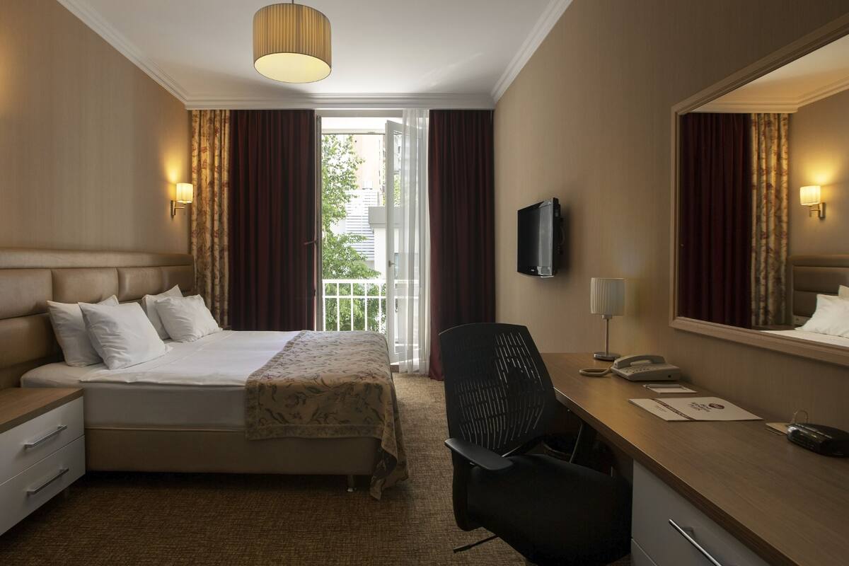 Habitación de hotel con cama, escritorio, silla y televisor.