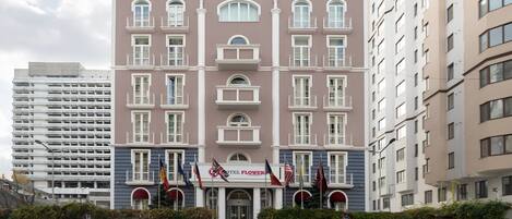 A multi-story hotel with a central entrance, balconies, and flags.