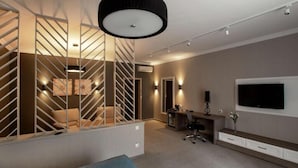A modern living room with a staircase, a TV, and a desk area. - Flowers Hotel (Chisinau)