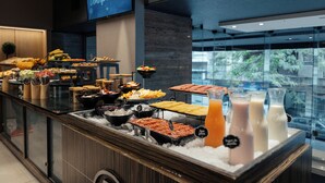 A breakfast buffet with various food items and beverages, a sign indicating 'Hugo's Domino de brunch', and a view of the outdoors through a glass wall. - Hotel Spa Republica (Mar del Plata)