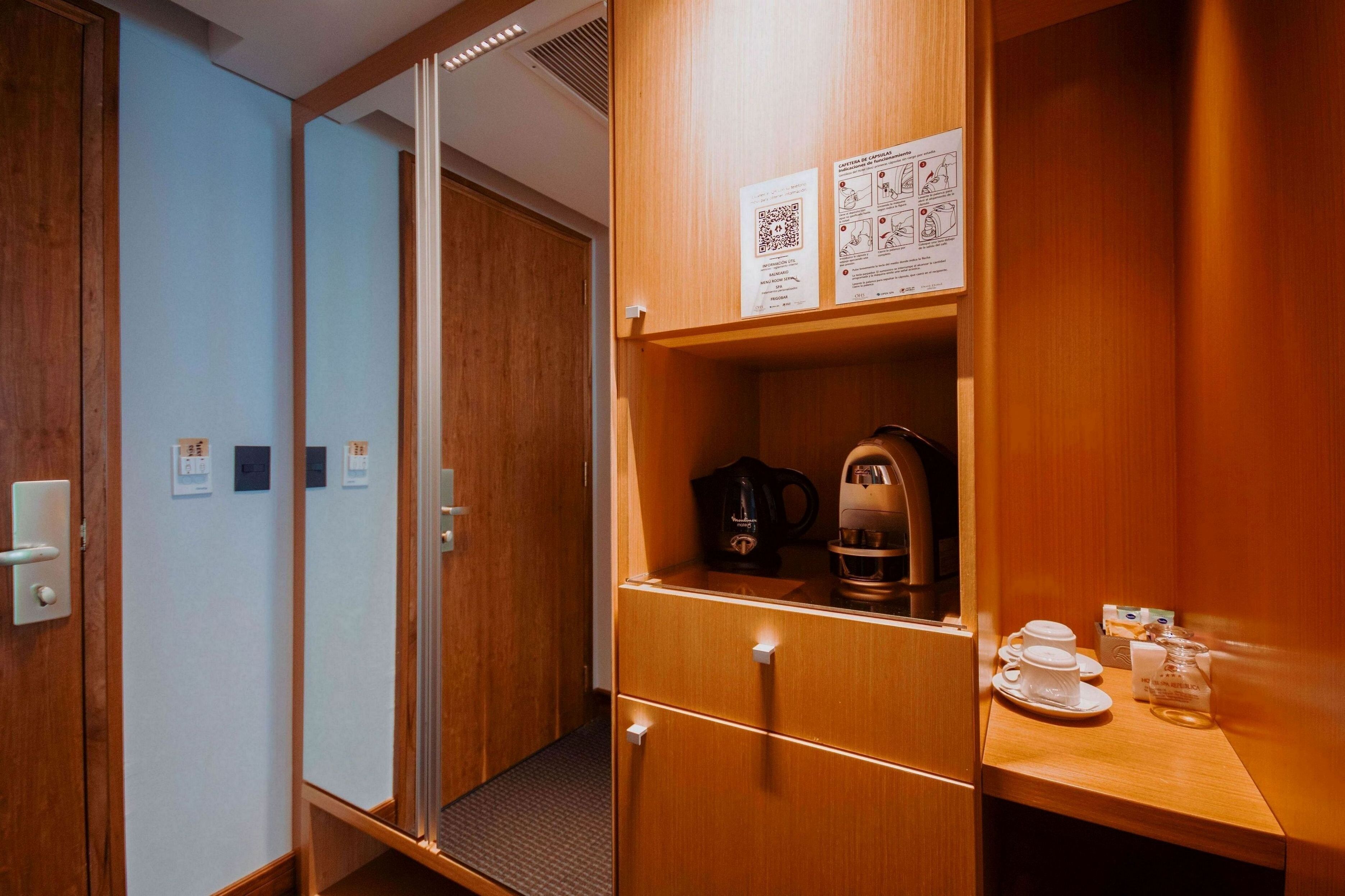Une chambre d’hôtel meublée en bois, avec une machine à café et un service à thé posé sur une petite table.