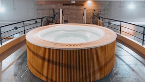 A circular hot tub with wooden accents, surrounded by a balcony with a railing, and a brick wall in the background. - Hotel Spa Republica (Mar del Plata)