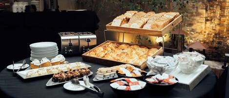 Una mesa de buffet con diversos pasteles, postres y pan.