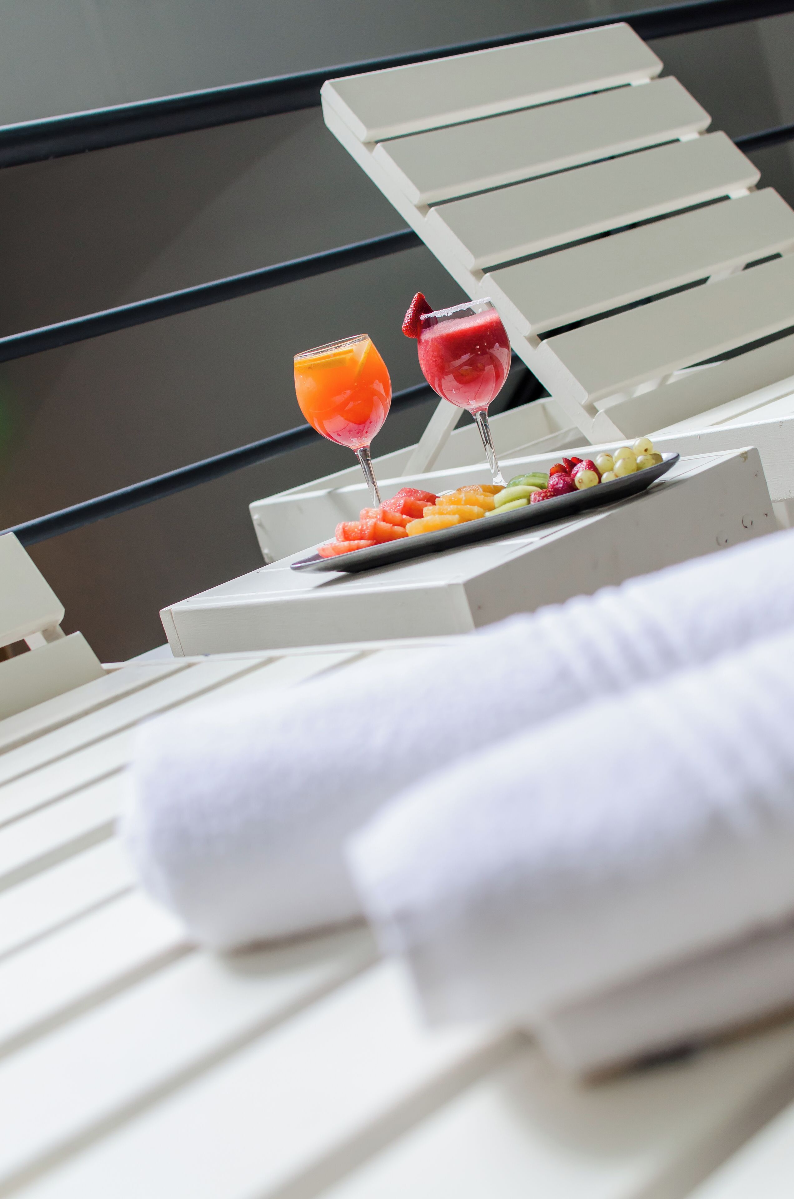 A sun lounger with a tray of fruit and two drinks.
