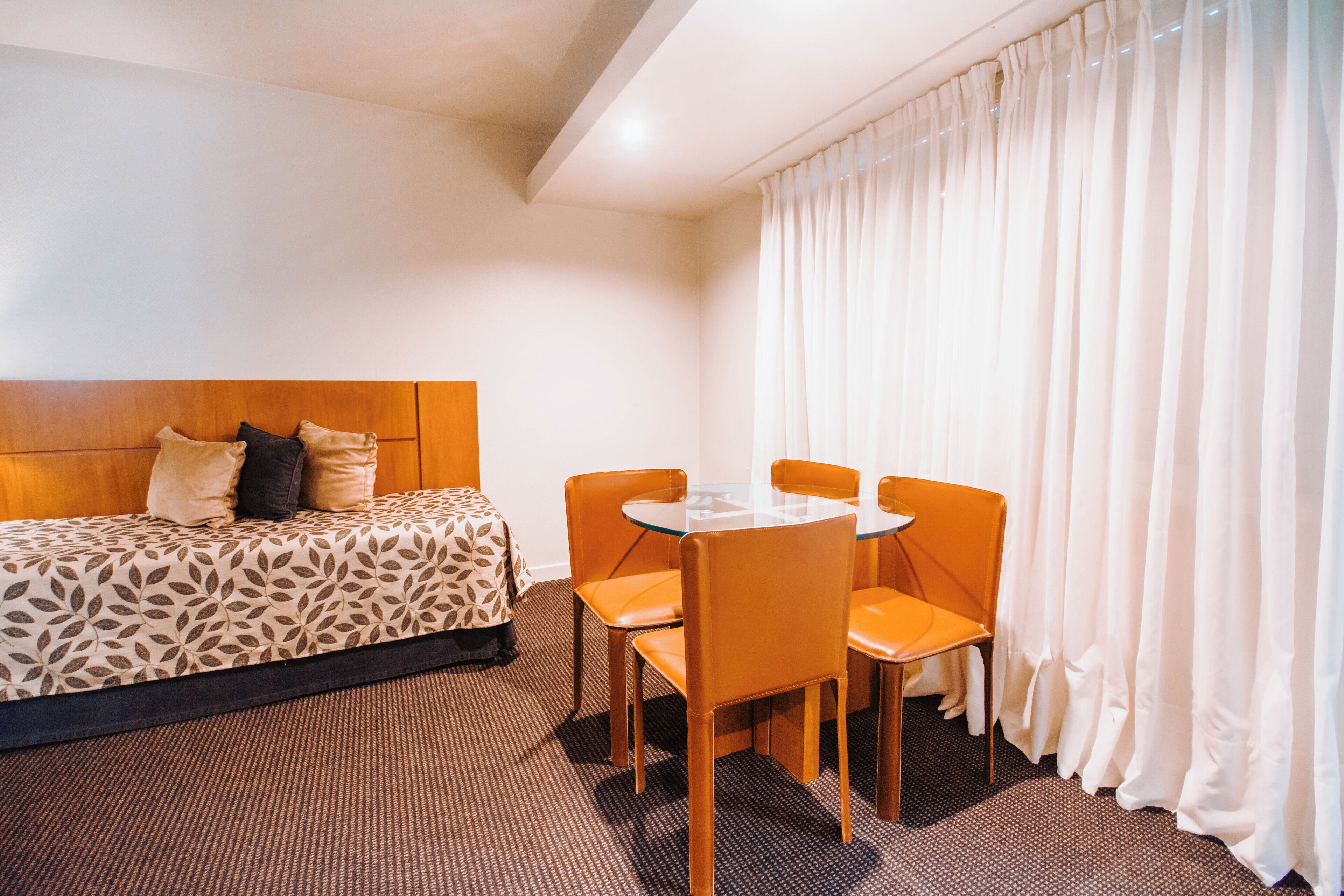 A hotel room with a bed, a table, and four chairs.