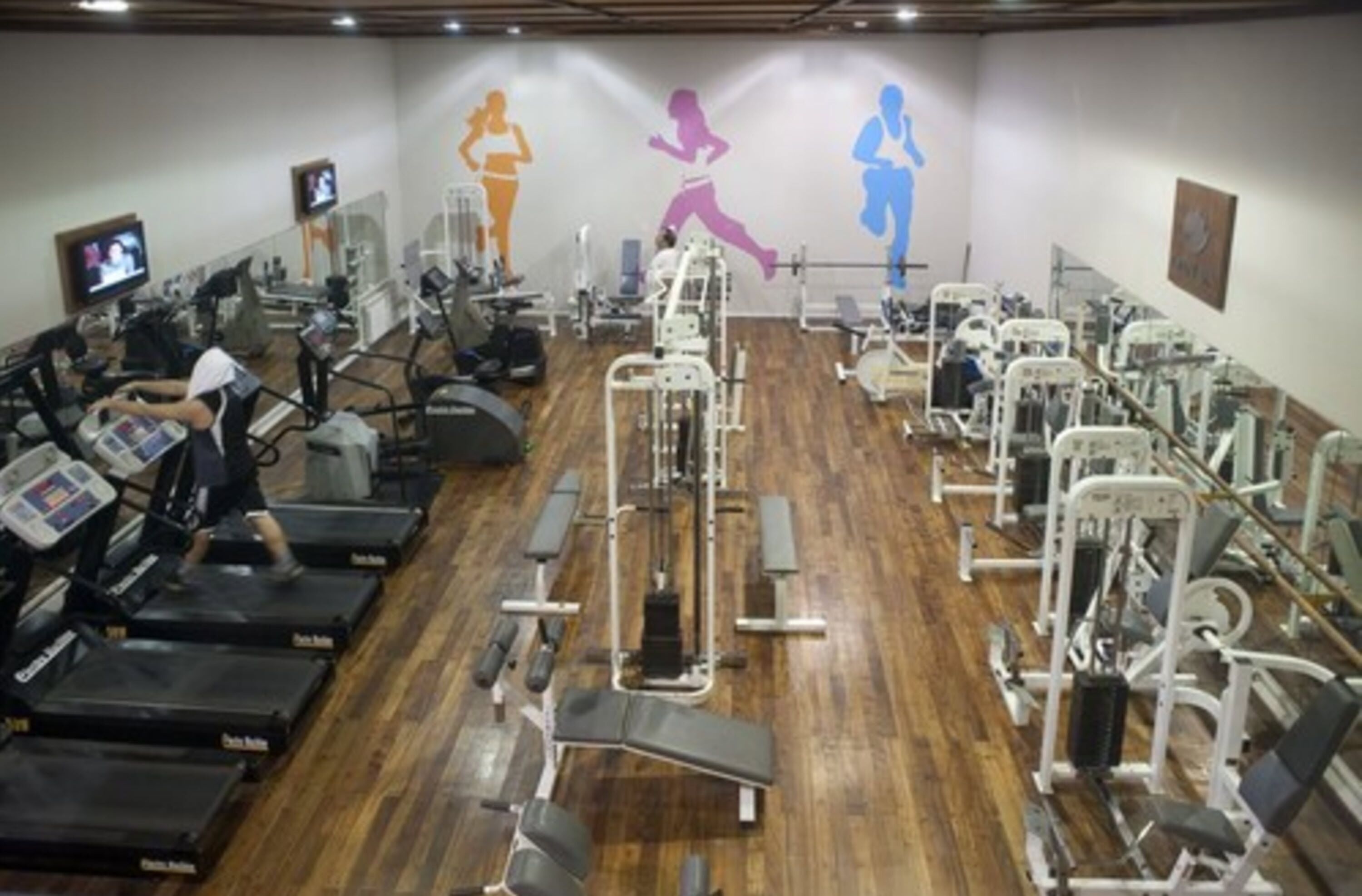 Ein Fitnessstudio mit Laufbändern, Krafttrainingsgeräten und Trainingsausrüstung.