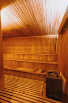 A sauna with wooden benches and a stone heating element.