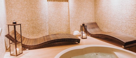 Un espacio de spa con una bañera de hidromasaje, escalones de madera y dos sillas reclinables.