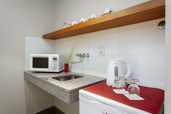 A small kitchenette with a microwave, sink, and coffee maker.