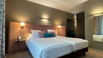 A double bed with white linens, two bedside lamps, and a nightstand with a phone and a sign.