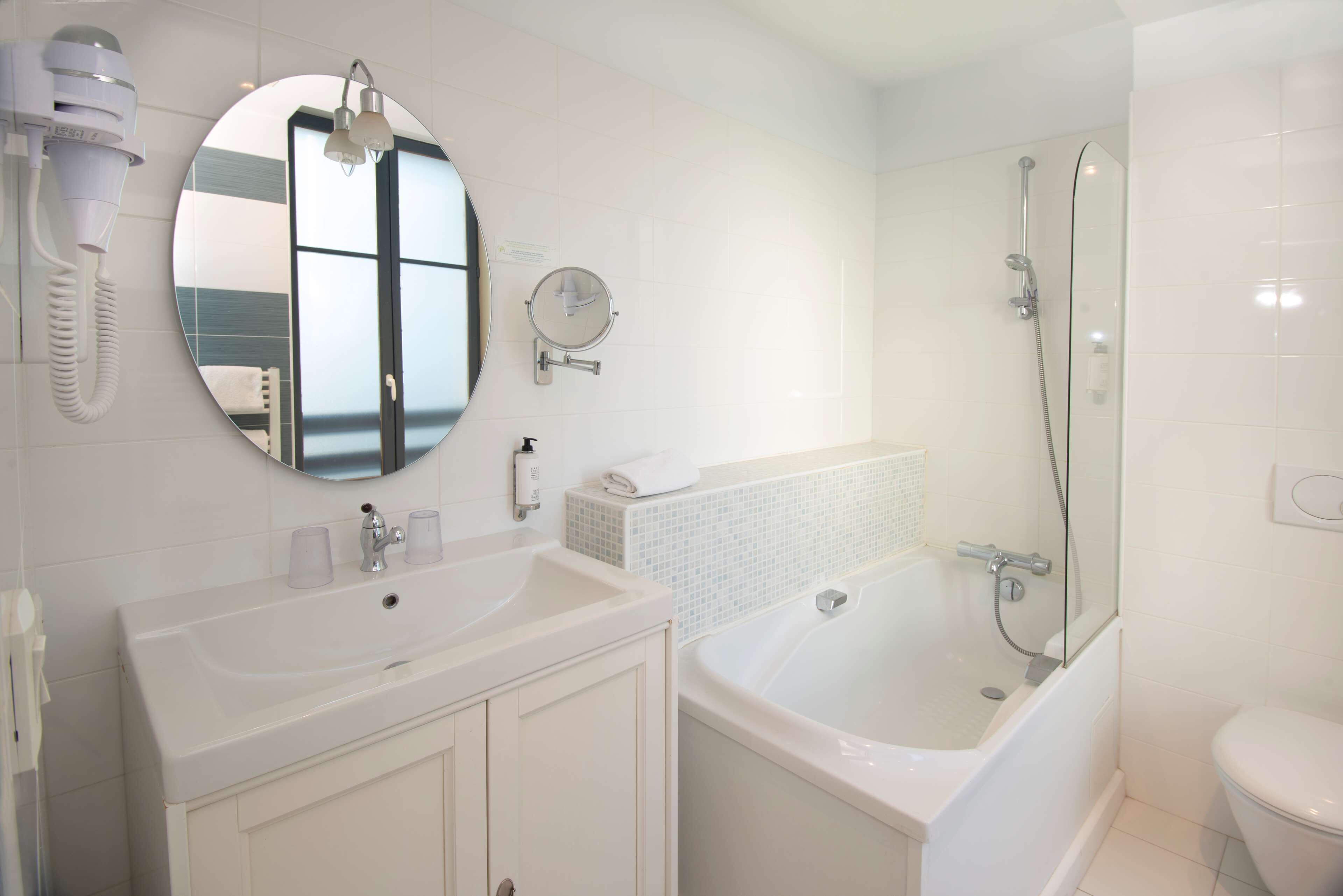 A modern bathroom with a white sink, mirror, and bathtub.