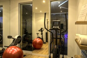 A home gym with exercise equipment, a large mirror, and a window with a view of trees.