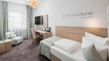 Een hotelkamer met een bed, een bureau, een stoel, een televisie en een muur met een bericht.