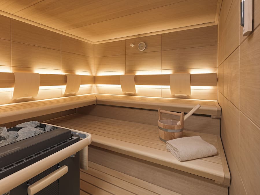Una sauna con bancos de madera, un perchero y un cubo de piedras.