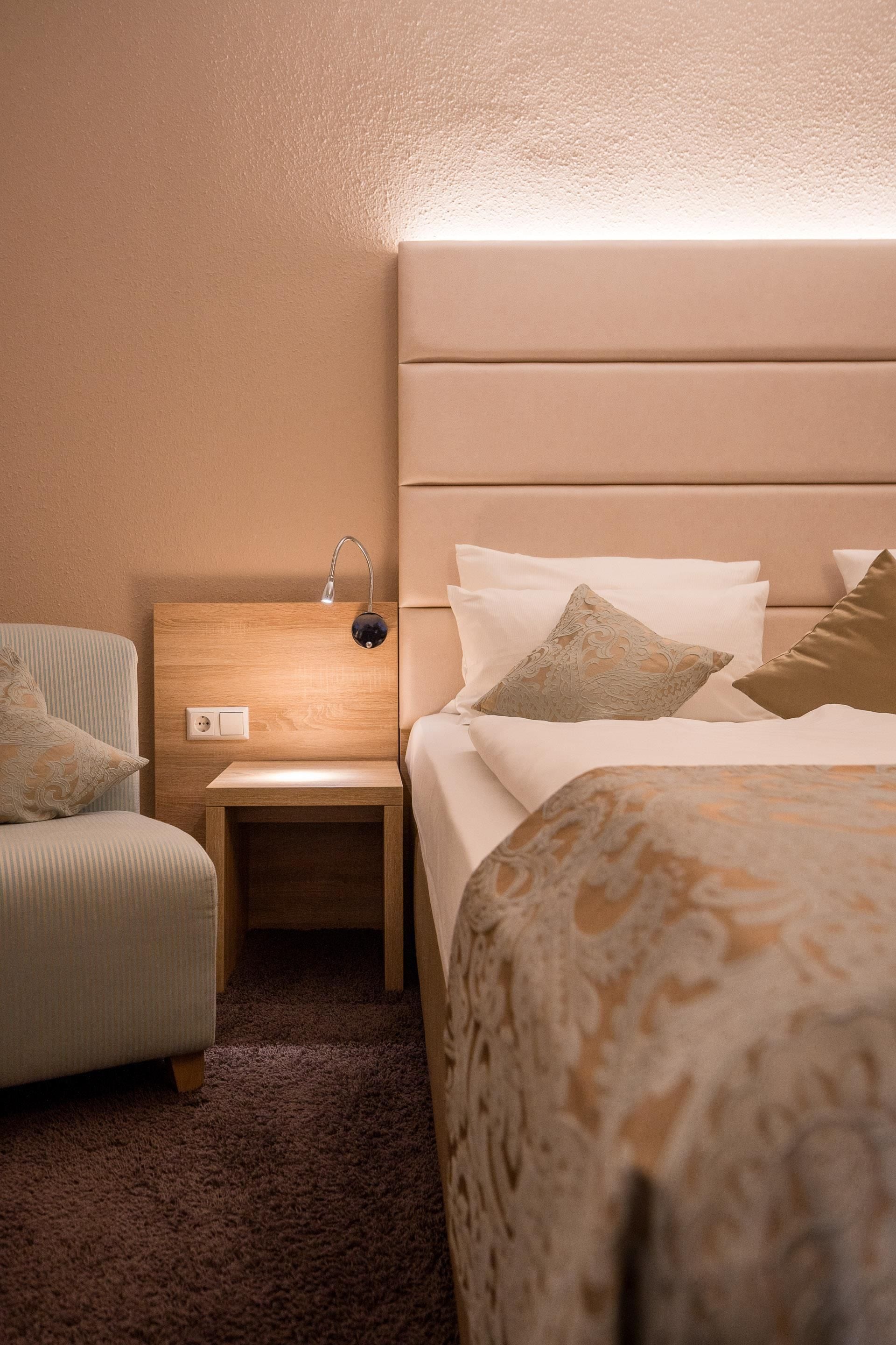 Une chambre d’hôtel avec un lit, une table de chevet, une lampe et une chaise.