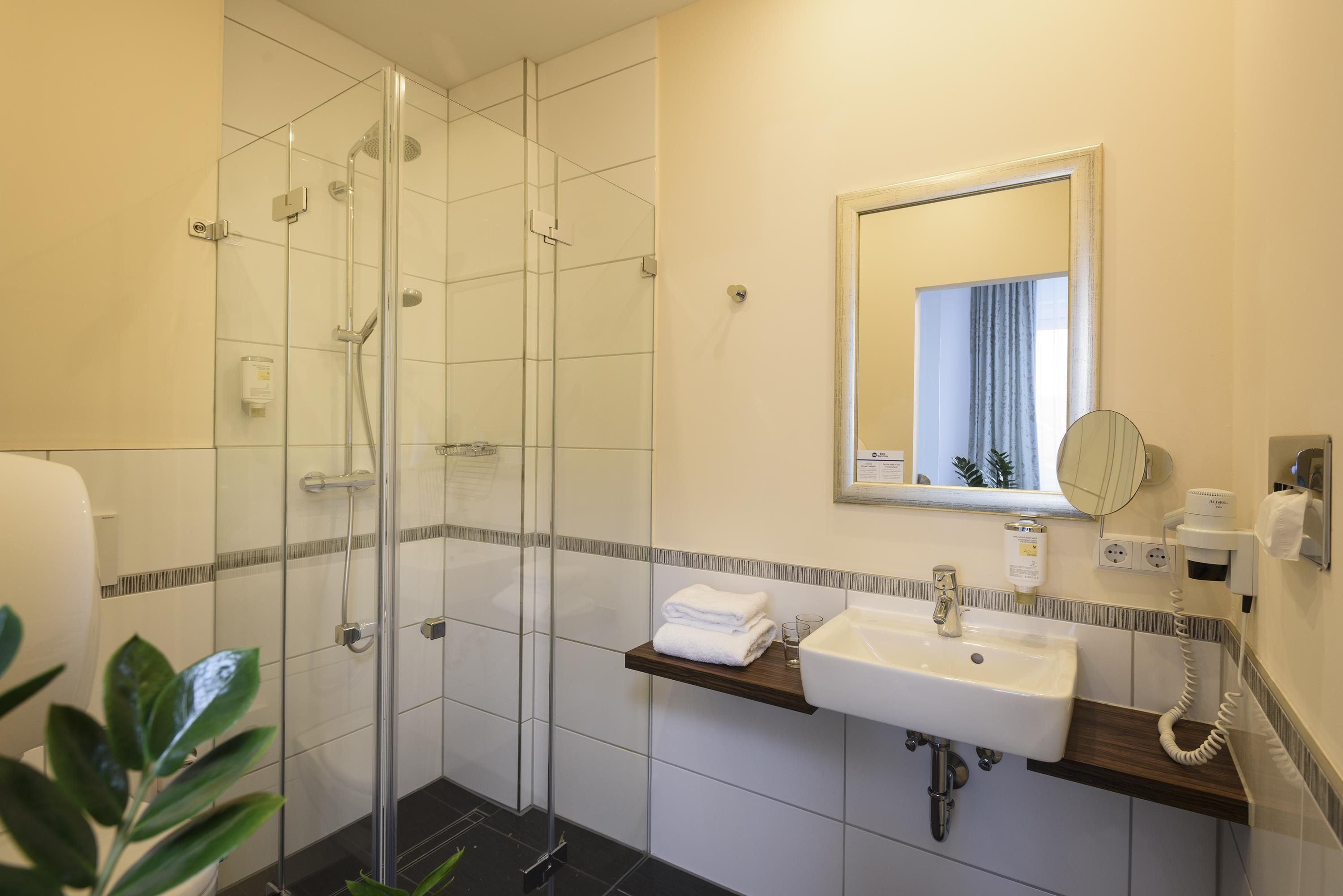 A modern bathroom with a glass-enclosed shower, a sink with a mirror, and a towel rack.