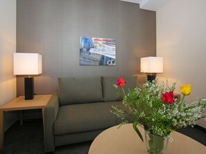 A hotel room with a sofa, two bedside tables with lamps, a vase with flowers, and a wall poster. - Best Western Hotel Lamm (Singen)