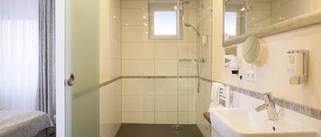 A hotel bathroom with a shower, a sink, and a mirror.