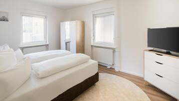Un dormitorio moderno con cama, televisor y armario.