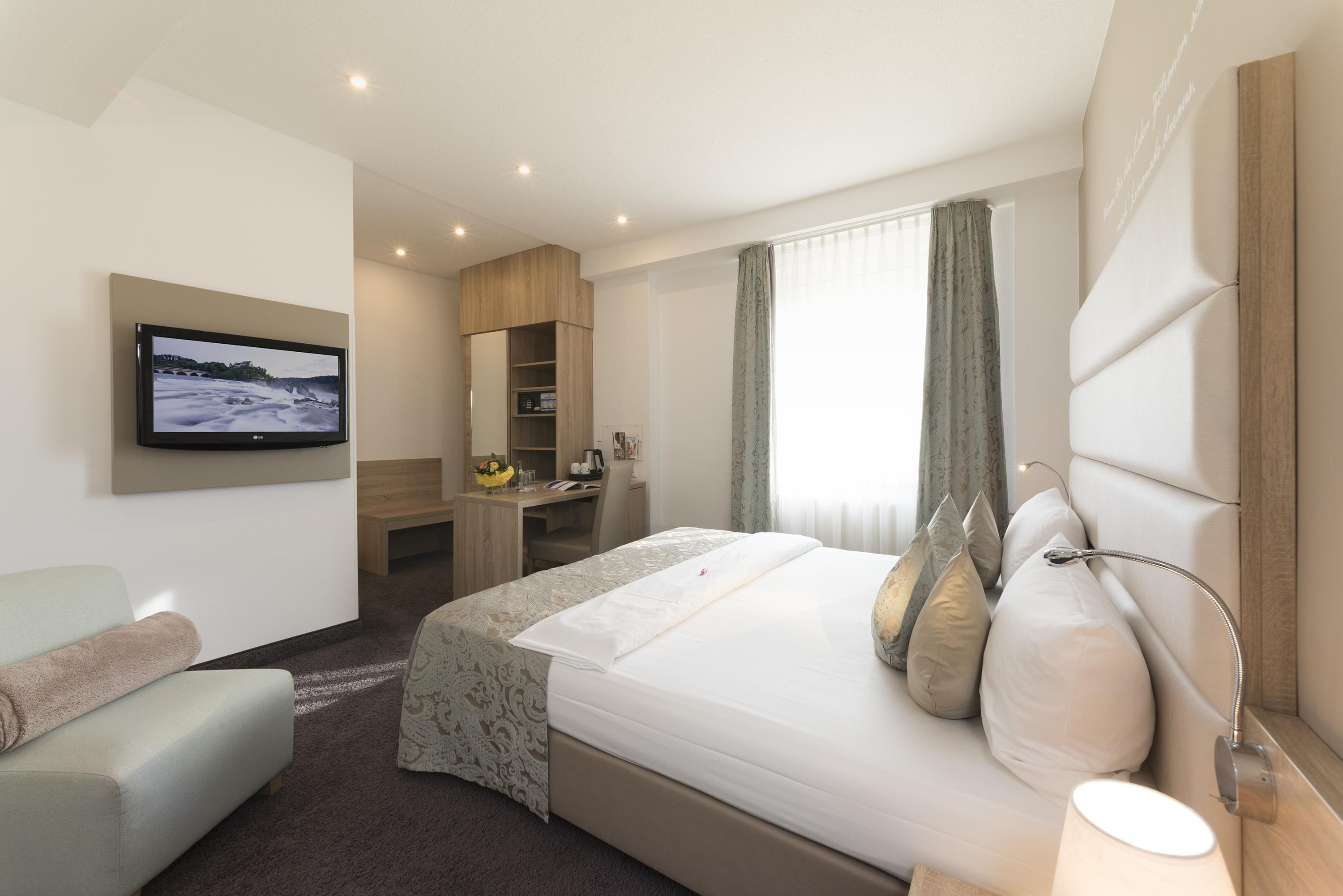A hotel room with a bed, a desk, a chair, a television, and a bathroom.