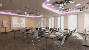 Une salle de conférence équipée de tables, de chaises et d’un écran de présentation à l’hôtel Lamm.