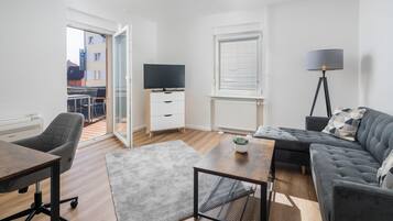 A modern living room with a sofa, a coffee table, a TV, and a floor lamp.