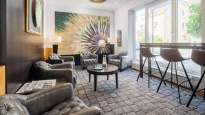 A modern lounge area with leather sofas, a round coffee table, and a large abstract painting.