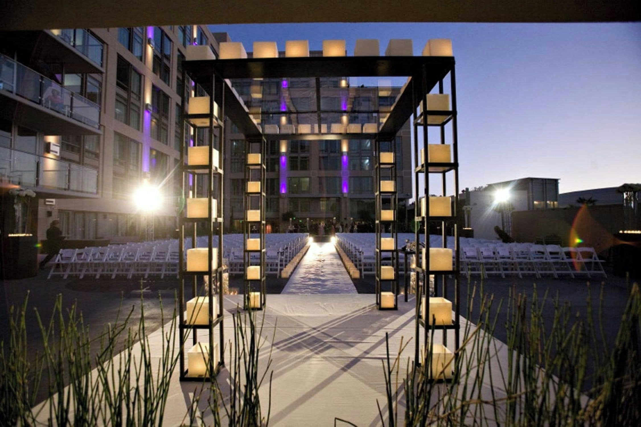 An outdoor event space with a canopy structure, seating, and ambient lighting.