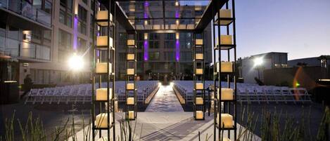 An outdoor event space with a canopy structure, seating, and ambient lighting.