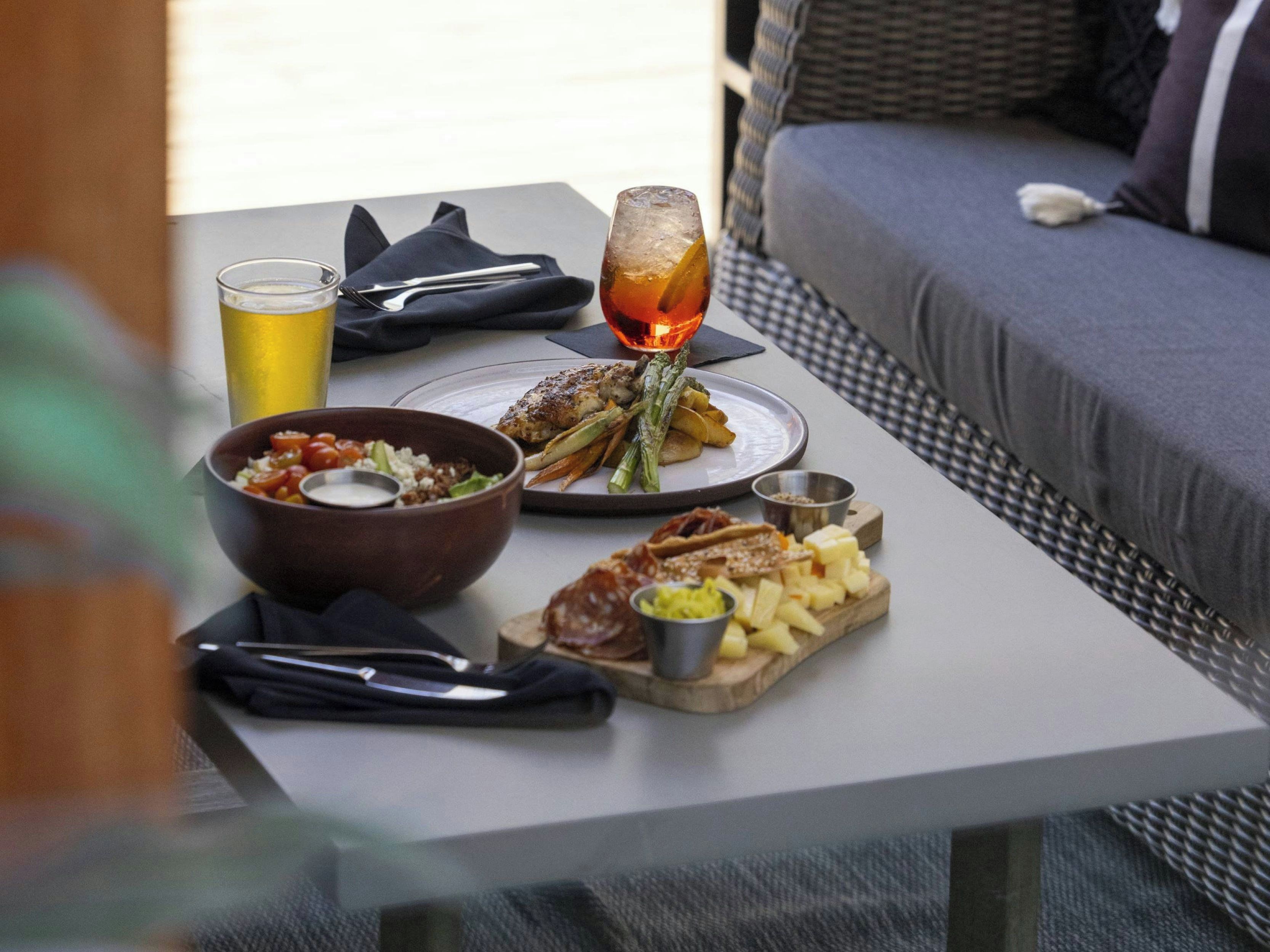 A dining table with a meal consisting of grilled chicken, asparagus, and potatoes, accompanied by a glass of a beverage and a bowl of salad.