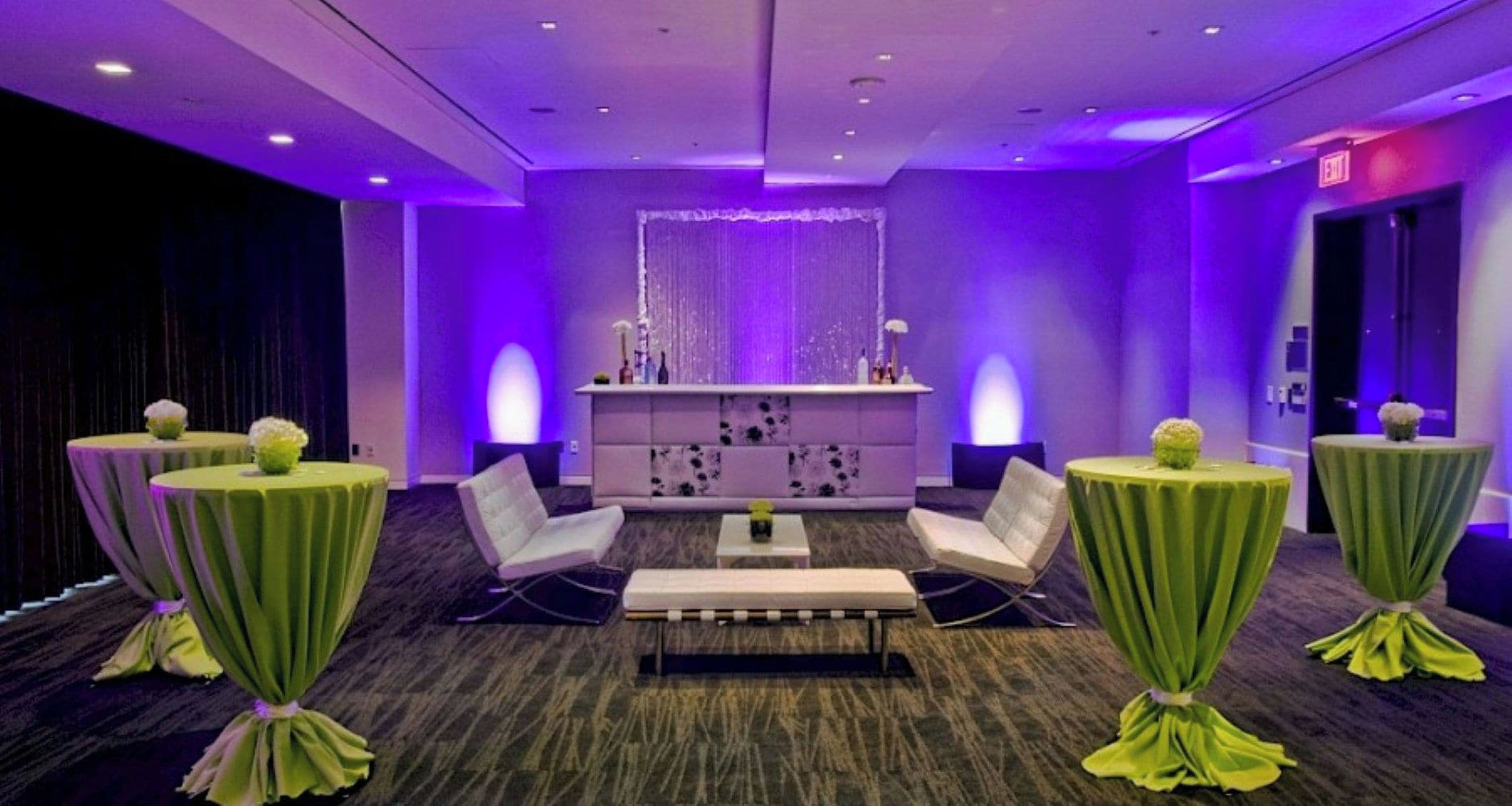 A modern lounge area with round tables, cushioned seating, and a central console.