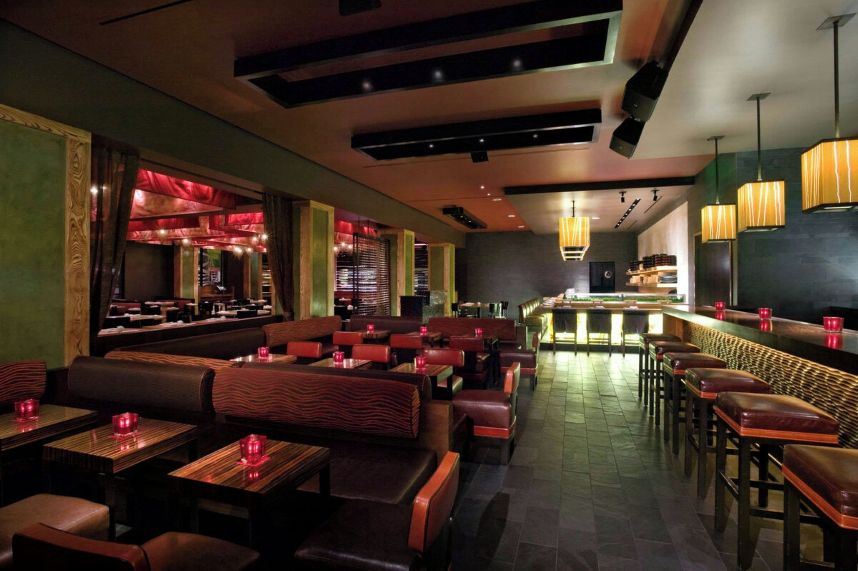 Interior de restaurant amb seients a cabines, taules i zona de bar.