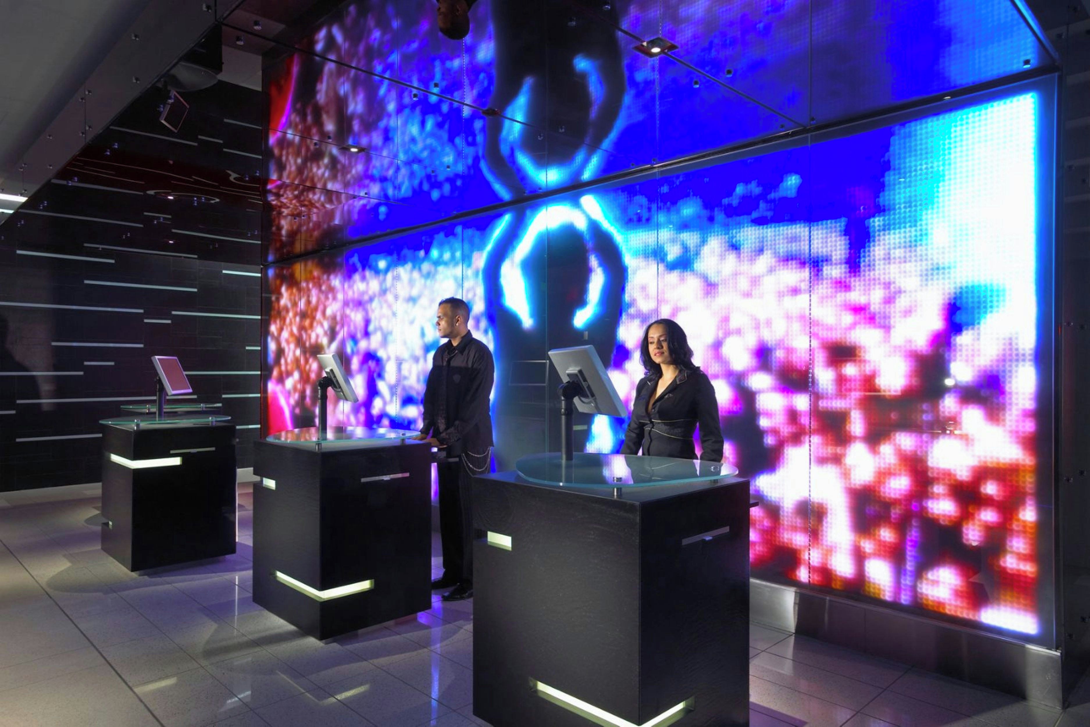 Un estudio moderno con dos presentadores en el atril, amplias pantallas LED al fondo y un diseño contemporáneo y elegante.